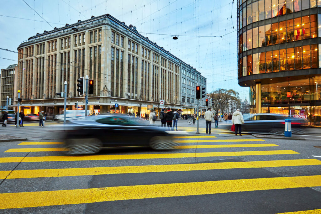 Autos fahren durch eine belebte Innenstadt mit Zebrastreifen bei einer Fahrt mit dem Auto Abo von Arval