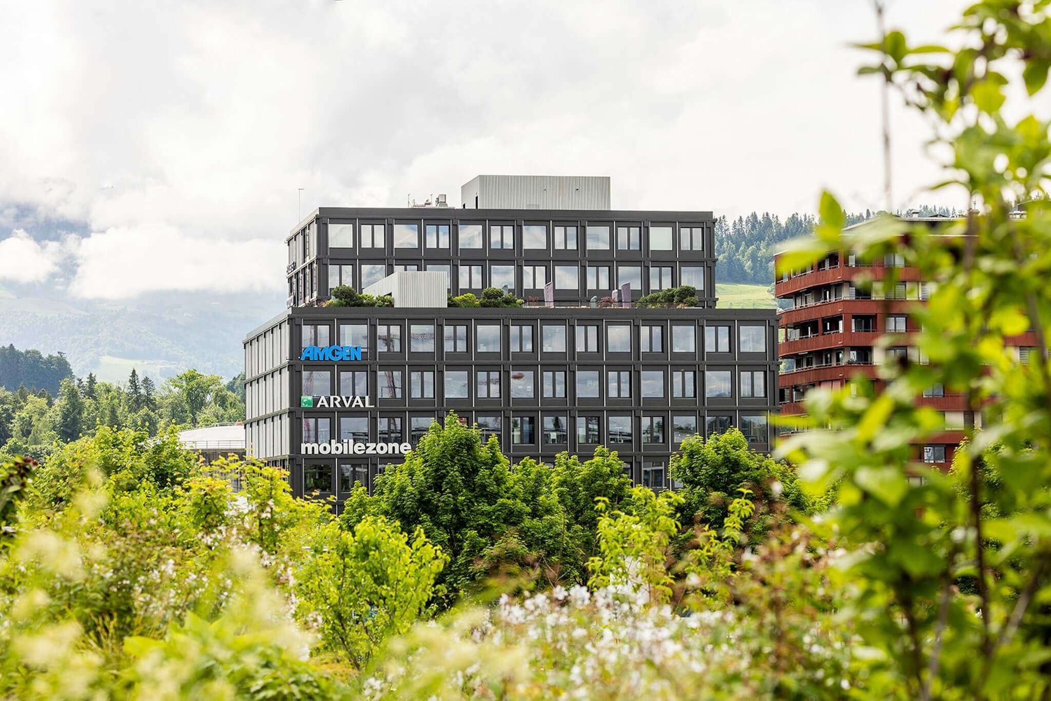 Modernes Bürogebäude der Arval Schweiz AG in Rotkreuz, umgeben von Bäumen.