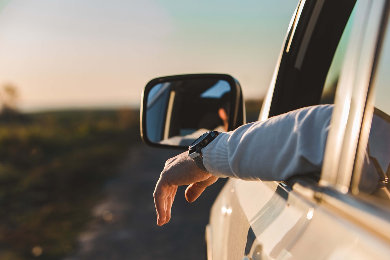 Eine Person lehnt den Arm aus dem geöffneten Fenster eines Arval Autos während der Fahrt.